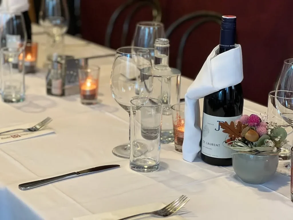 Festlich gedeckte lange Tafel mit Gläsern, Wein und Kerzenlicht