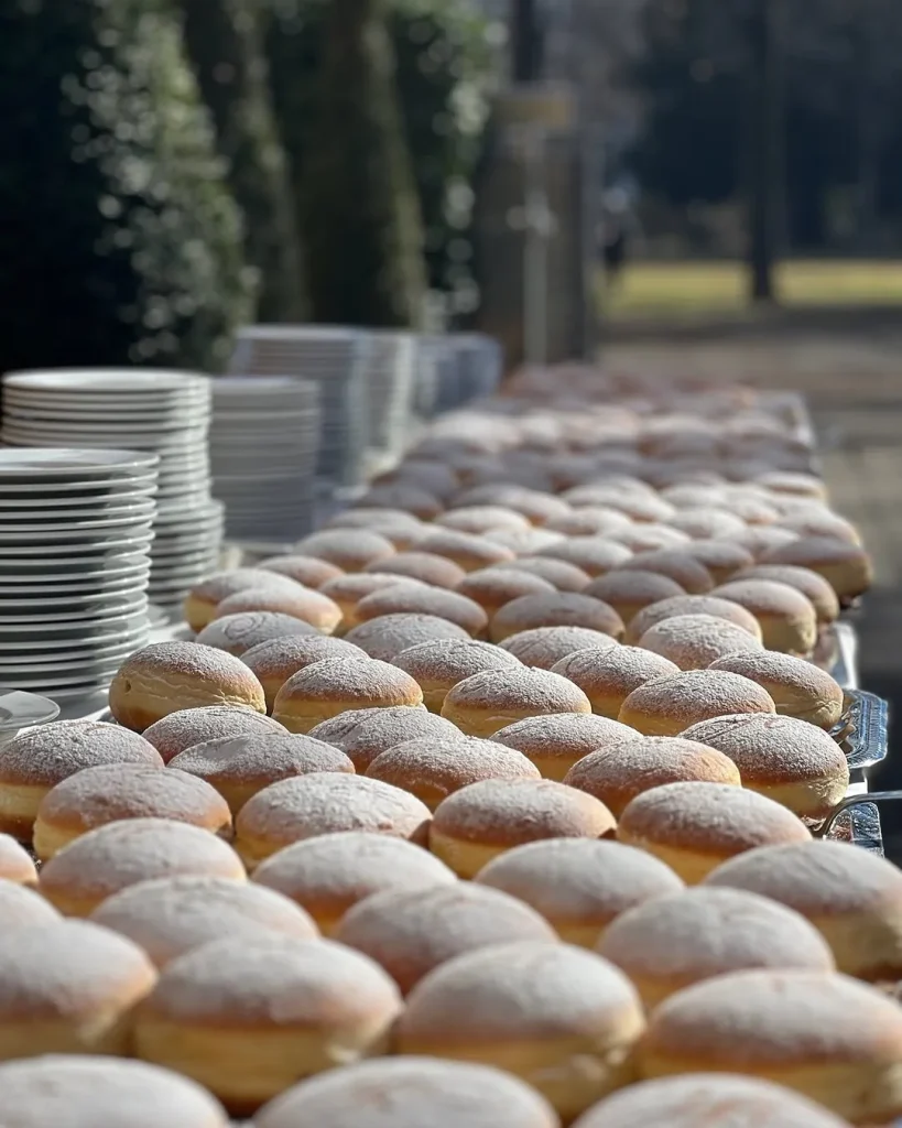 Reihen frisch gebackener Krapfen mit Staubzucker aus der eigenen Backstube