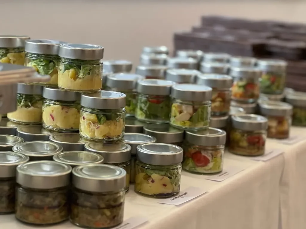 Portionsweise abgefüllte Salate und Aufstriche in Weckgläsern auf dem Cateringtisch