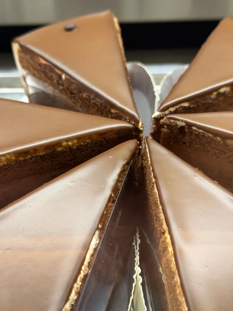Ganze Sachertorte mit glänzender Schokoglasur, in Stücke geschnitten