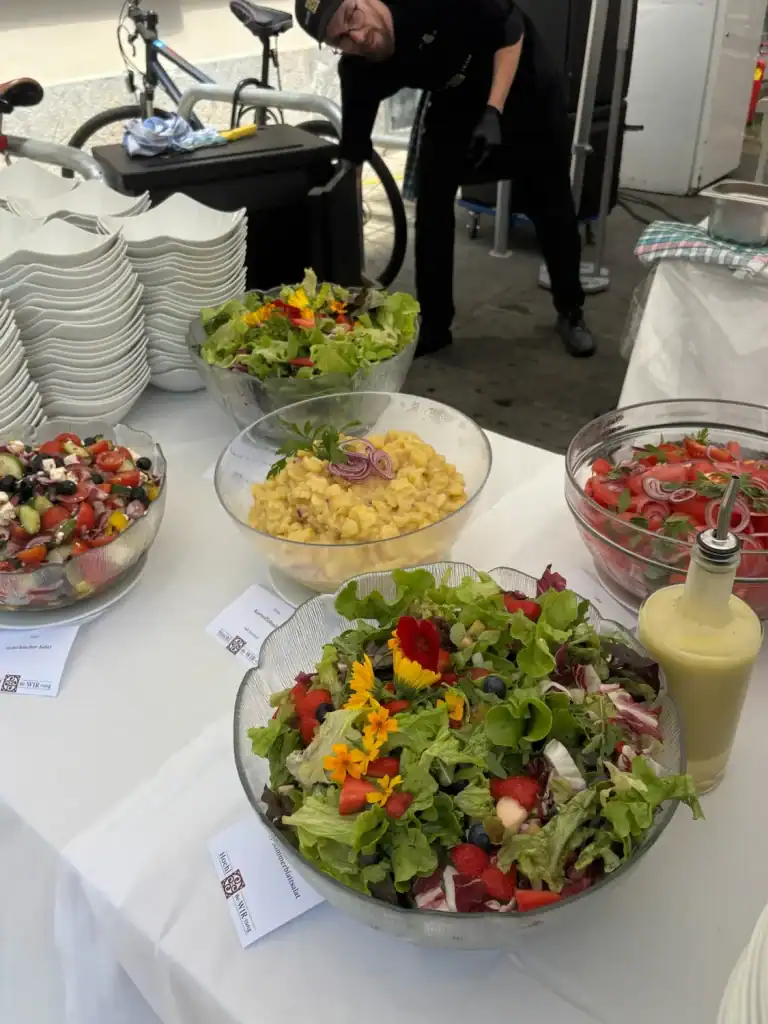 Bunte Salate und Dressing auf einem Catering-Tisch.