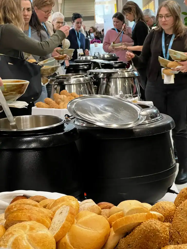 Menschen beim Buffet mit warmen Speisen und Brötchen.