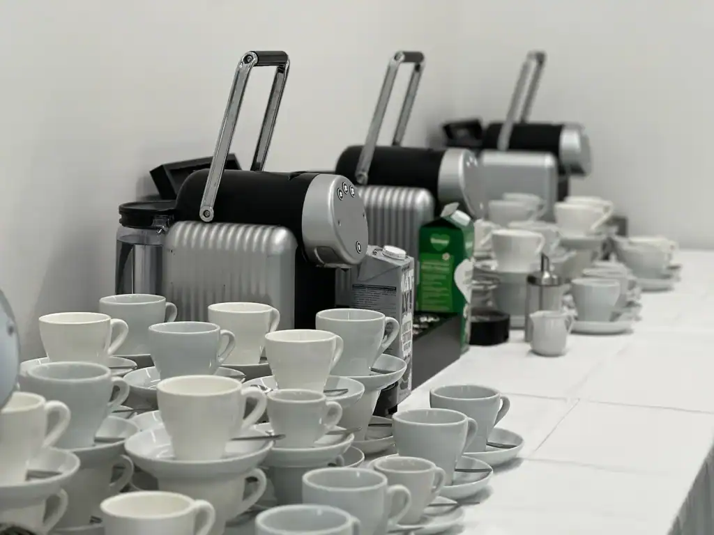 Mehrere Kaffeemaschinen mit weißen Tassen und Untertassen.