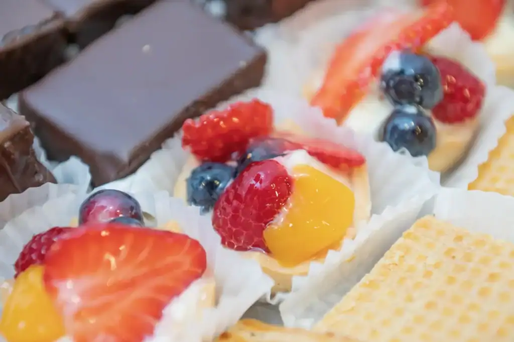 Frucht-Törtchen mit Beeren und Mango auf einem Teller.