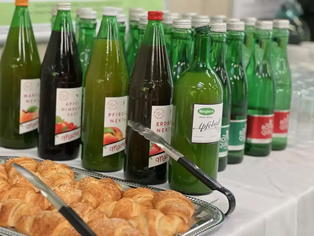Verschiedene Flaschen mit Fruchtsäften und Gebäck auf einem Tisch.