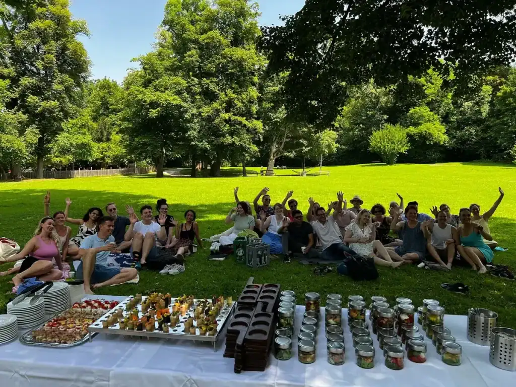 Gruppe von Menschen beim Picknick im Park mit Essen und Getränken.