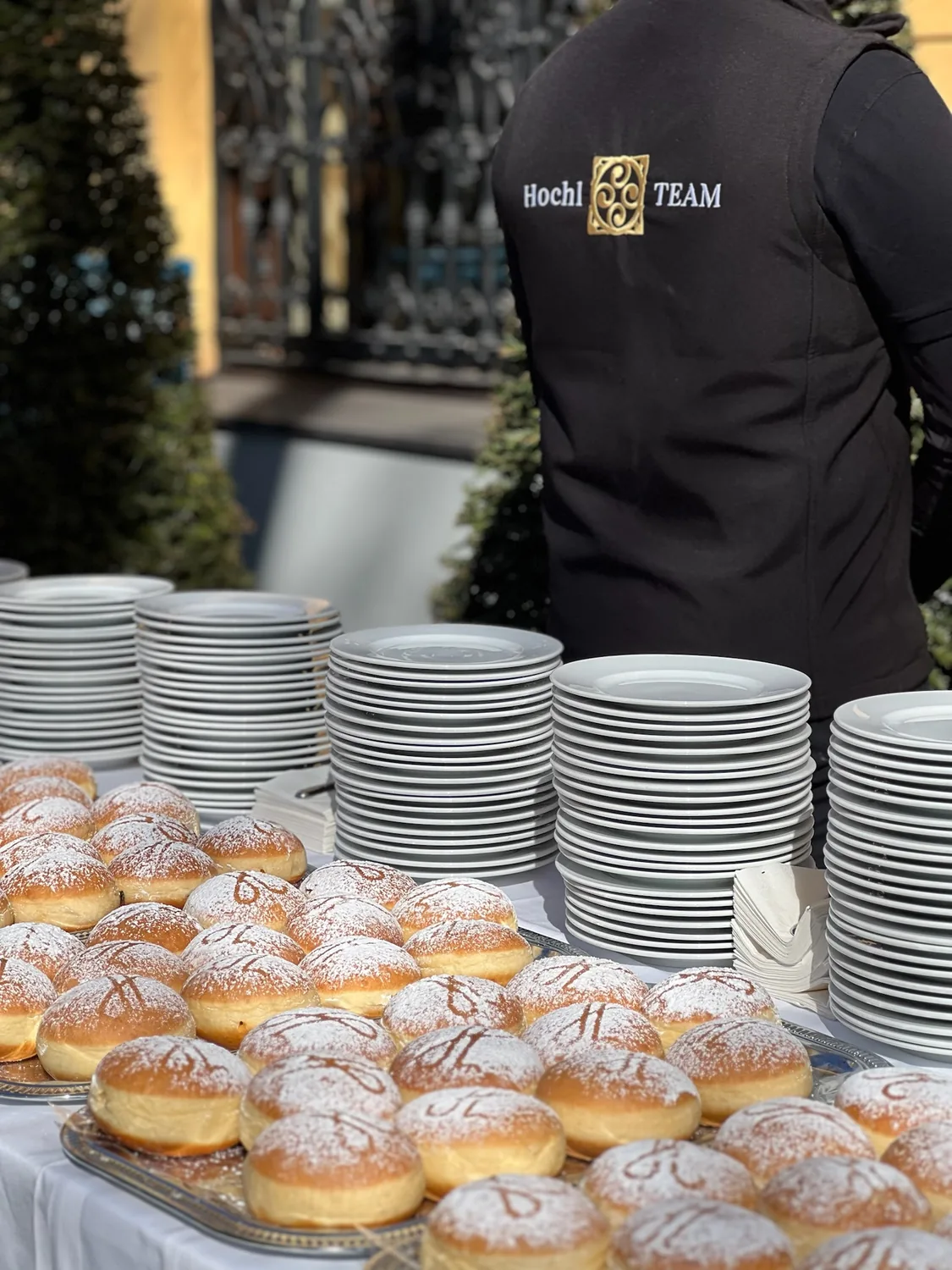 Bleche mit frischen Krapfen, dahinter ein Mitarbeiter von Hochl Be-WIR-tung