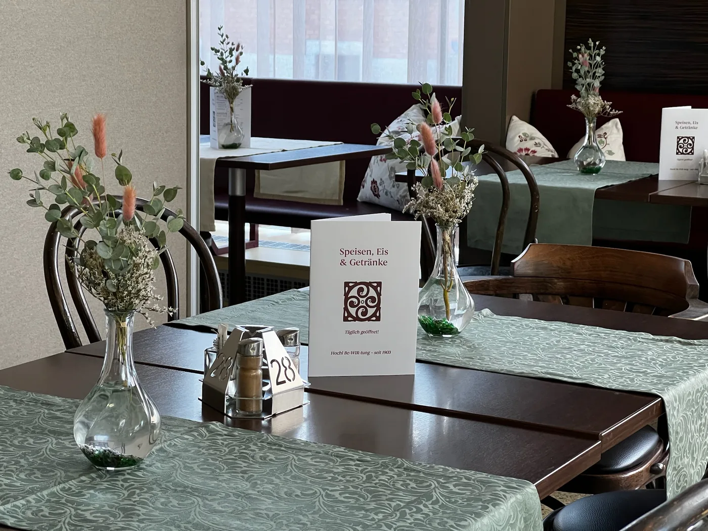 Tischreihe mit Blumen im Gastraum